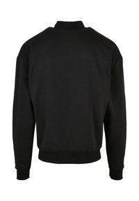 Svart sweatshirt med rund hals, lange ermer og ribbestrikkede mansjetter. Laget av et mykt, teksturert materiale med avslappet passform.