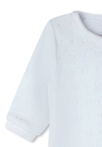 Vêtement à manches longues blanches en tissu doux texturé avec de petits motifs en forme de cœur, col rond et poignets.