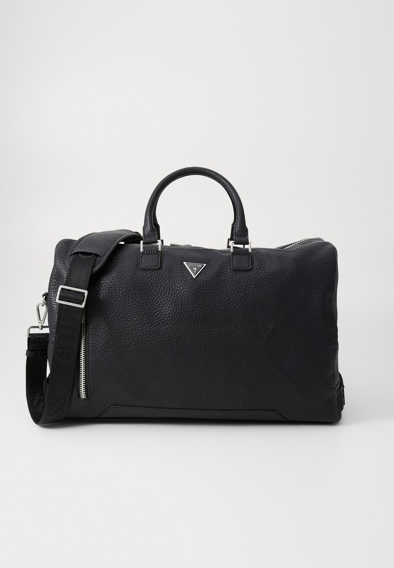 Sac de sport en cuir noir texturé avec deux poignées, une sangle amovible, des garnitures en argent et un accent de logo métallique à l'avant.