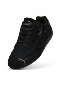 Sorte ruskinds sneakers med lavt design, der har sorte snørebånd, et sølvfarvet Puma-logo og teksturdetaljer på siderne.
