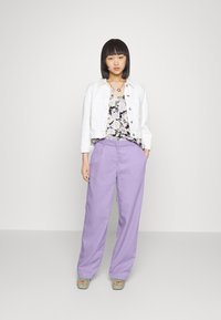 Casaco de ganga branco, top preto floral, calças largas lilás, sapatos de plataforma verdes e um colar de contas. Design simples e contemporâneo.