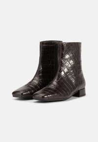Bottines brillantes en cuir marron foncé avec texture crocodile, fermeture éclair sur le côté, bout carré et petit talon block, sur un fond blanc.