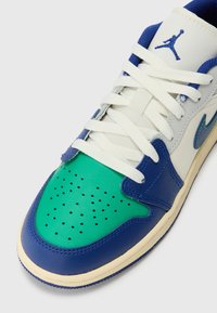 Sneaker con una toma superiore in mesh bianco e pelle, punta verde, accenti blu, dettagli perforati e lacci bianchi. Caratterizzato da un logo laterale.