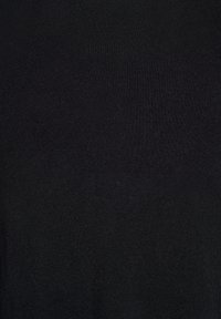 Lähikuva yksivärisestä mustasta neuloksesta, jossa on hieno, tasainen rakenne ja näkyvä ompelukuviio.