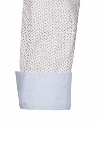 Cuff di camicia bianca con piccoli motivi a mezzaluna viola, con un accento di tessuto testurizzato azzurro chiaro all'orlo. Focus sul design geometrico.