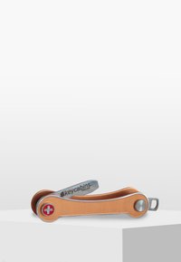 Porte-clés multifonction en cuir orange et métal argenté, avec un emblème de croix suisse et un attache-clé circulaire.