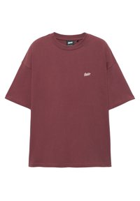 T-shirt oversize à manches courtes couleur bordeaux avec petit logo script blanc sur le côté gauche de la poitrine et col rond sur fond blanc.