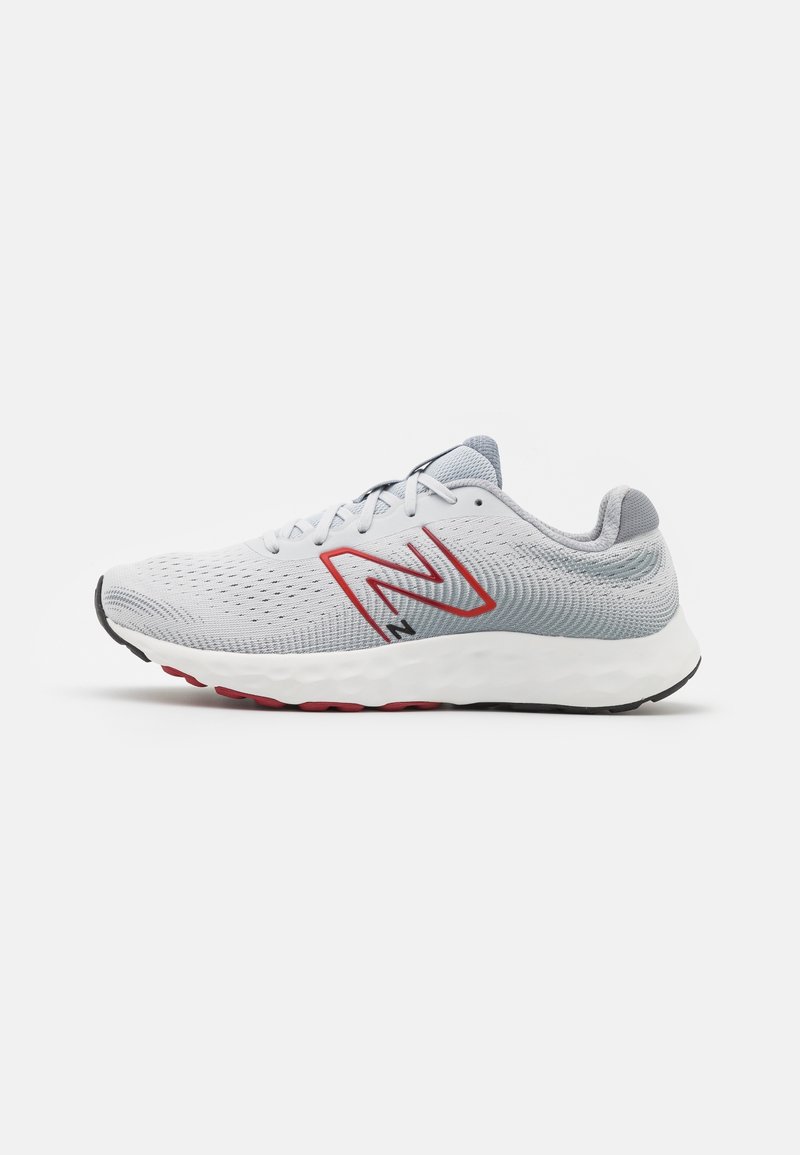 Chaussure de course gris clair et blanc avec logo "N" rouge, tige en mesh, semelle blanche amortissante, accents de semelle en noir et rouge, vue latérale.