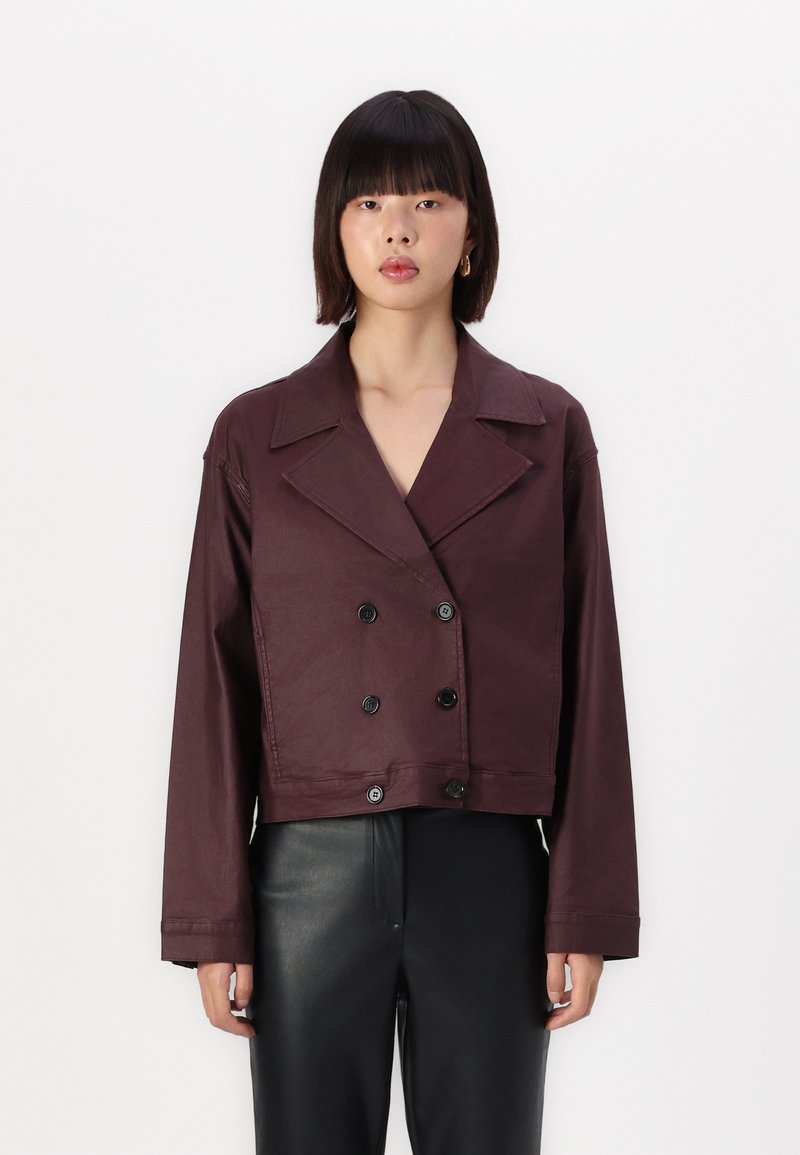 Bordeaux cropped dubbelbreasted jasje in een glad materiaal, met grote zwarte knopen en een brede kraag, gecombineerd met zwarte broek.