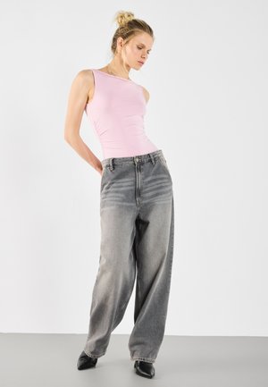 Un top roz fără mâneci, ajustat, asortat cu blugi gri, evazați, cu talie înaltă și modele estompate. Modelul poartă tocuri negre ascuțite.