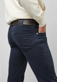 Donkerblauwe katoen jeans met een slim fit, voorzien van achterzakken en een bruine leren riem met stiksel-detail.