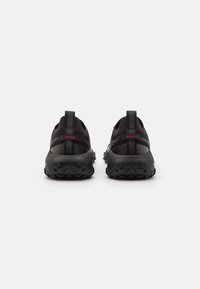 Černé sportovní boty s prodyšným síťovinovým svrškem, pevným gumovým podešví a jemnými červenými logy na zadní části.