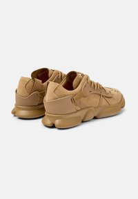 Beige Wildledersneaker mit strukturierten Gummisohlen, runder Zehenform und gepolstertem Kragen; mit gestickten Akzenten und einem markierten Zugband.