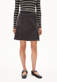 Grijze corduroy rok met een licht uitlopende silhouet, midi-lengte, gecombineerd met zwarte ballerina's met een gesp met studs. Gestreepte lange mouwen top.