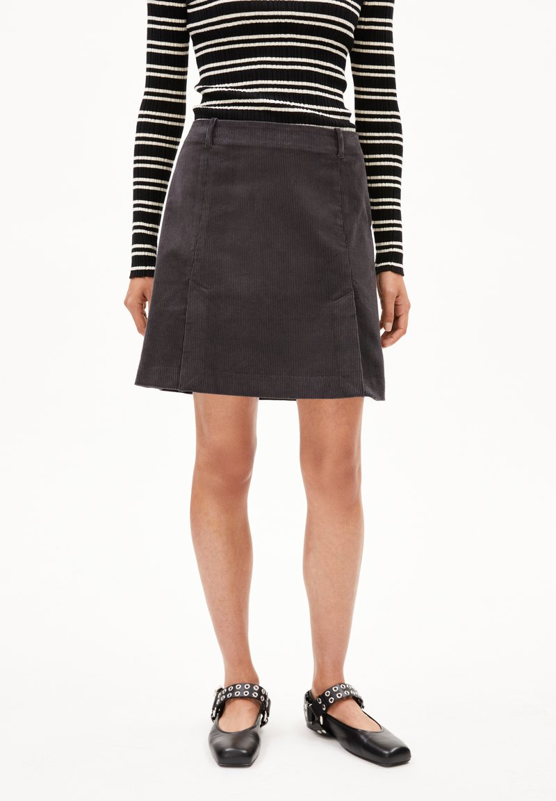 Grijze corduroy rok met een licht uitlopende silhouet, midi-lengte, gecombineerd met zwarte ballerina's met een gesp met studs. Gestreepte lange mouwen top.