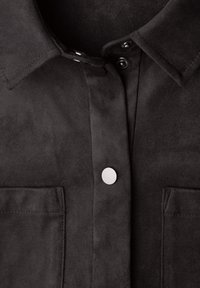 Camisa de ante gris oscuro con cuello estructurado, cierre frontal con botones a presión y dos bolsillos en el pecho. Textura suave y acabado mate.