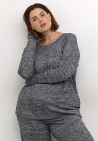 Hallhalli tekstuuriga pikakä sleeves topp, millel on ümmargune kaelus, koos sobivate hallide pükstega. Kangas näib olevat pehme ja mugav, omades peent mustrit.