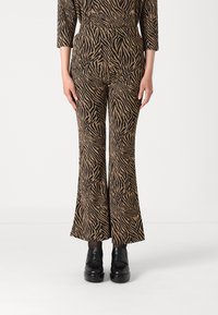 Pantalons évasés en imprimé zèbre noir et or, dotés d'un tissu extensible et d'une taille haute. Assortis à des chaussures à plateforme noires.