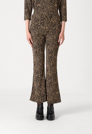 Slengbukser i sort og guld zebra print, med et strækbart stof og høj talje. Kombinert med sorte platåsko.