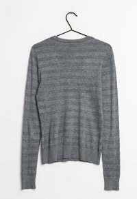 Maglione grigio a maniche lunghe con orlo a coste, caratterizzato da un motivo a righe con sottili variazioni di trama e un cappio pendente sul collo.