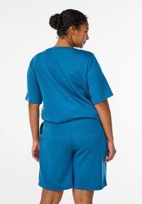 Türkisfarbenes Baumwollmischungs-Outfit mit kurzärmligem Oberteil und knielangen Shorts, lockerer Passform und glatter Textur. Einfaches, funktionales Design.