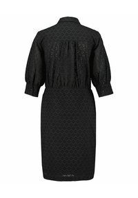 Vestito nero con colletto abbottonato, maniche a sbuffo e vita arricciata. Realizzato in tessuto testurizzato con un motivo a ritaglio geometrico.