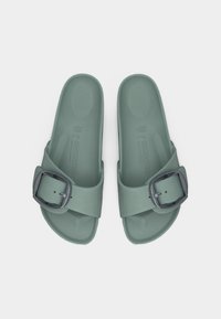 Ζευγάρι πράσινα σανδάλια με μία λωρίδα και μεγάλη μαύρη αγκράφα, μέγεθος 36, της μάρκας Birkenstock, σε λευκό φόντο.