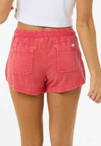 Pantaloni corti corallo realizzati in tessuto strutturato, con vita elasticizzata, due tasche posteriori e un piccolo etichetta del marchio sulla tasca sinistra.