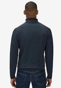 Marinblå tröja med ribbad hög krage och muddar, slät textur, slim fit-design och en enkel bakvy.