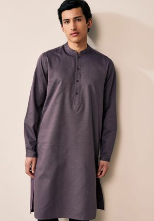 Duga rukava, tamnoljubičasta kurta s mandarin ovratnikom, koja ima dugmad i bočne proreze za lakše kretanje. Detalj s teksturiranom tkaninom.