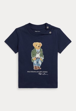 Mørkeblå barnetrøje med knap ved skulderen, prydet med en bjørn i casual lag-på-lag outfit og teksten "Polo Bear by Ralph Lauren" nedenfor.