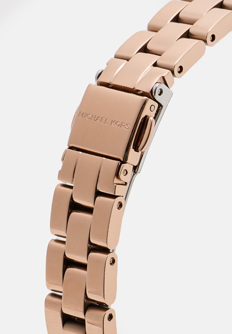Bracelet de montre en métal rose gold avec une finition polie, doté de maillons rectangulaires et d'un fermoir sécurisé gravé de "MICHAEL KORS."