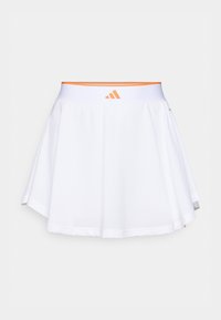 Λευκή αθλητική φούστα με υφή από δίχτυ, φαρδιά σχεδίαση και ελαστική μέση με πορτοκαλί λογότυπο. Το τελείωμα είναι κυρτό για επιπλέον λεπτομέ ρεια.