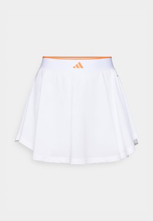 Bijela sportska suknja s mrežastom teksturom, proširenim krojem i elastičnim pojasom na kojem je narančasti logo. Rub je zakrivljen za dodatni detalj.