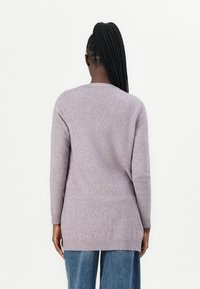 Helle lila, langärmeliger Pullover mit runder Ausschnitt und geripptem Saum, der eine weiche Textur und eine lockere Passform aufweist, getragen über Jeans mit weitem Bein.