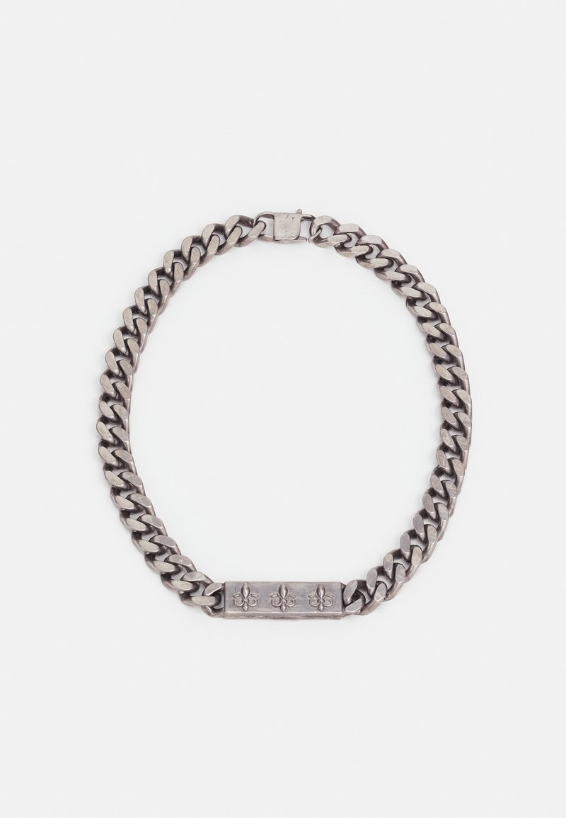 Bracelet chaîne épaisse couleur argent avec une plaque rectangulaire ornée de trois symboles fleur-de-lis gravés et une fermeture à boîte.