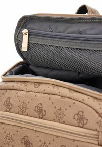 Sac à main en tissu marron avec un extérieur texturé et un motif subtil. L'intérieur comprend une poche zippée en filet grise et une doublure noire.