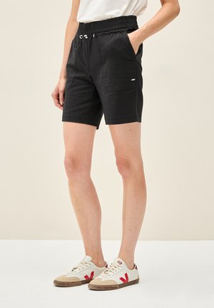 Pantaloni shorts neri con vita elastica e lacci, dotati di tasche laterali e un piccolo dettaglio con logo sulla parte anteriore. Tessuto misto cotone.