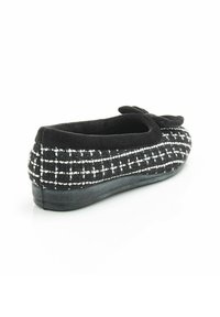 Mocassin noir avec une surface tissée texturée présentant un motif de grille blanche, un bout arrondi et un dessus en tissu doux agrémenté d'un accent en forme de nœud.