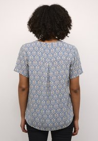 Blå og beige mønstret kortærmet skjorte med rundet kant og plissee bagpå, lavet af letvægtsstof, med et blomstermønster.