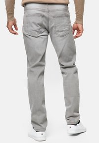 Jeans de mezclilla gris con un diseño de pierna recta, que cuentan con dos bolsillos traseros y una textura suave. Combinados con zapatillas blancas.