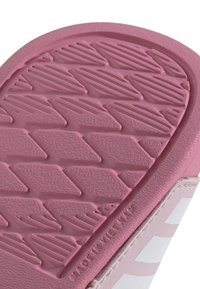 Sola in gomma rosa con un motivo di presa testurizzato che presenta diamanti e scanalature diagonali. Il pannello laterale mostra strisce bianche su uno sfondo rosa abbinato.