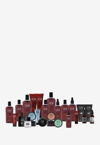 Kollektion av hårvårdsprodukter i olika behållare; röda flaskor och tuber med svarta och vita etiketter; runda och rektangulära former.