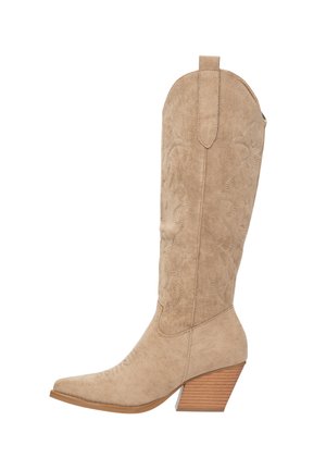 Botte beige en daim style western avec bout pointu, motifs de couture verticaux et talon en bois empilé.