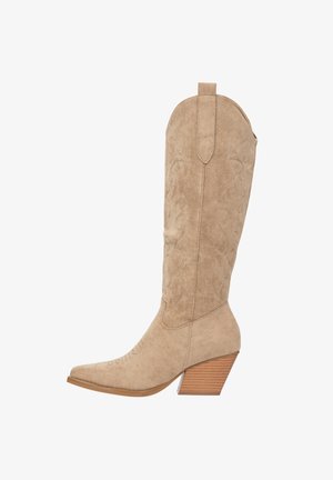 Beige suède westernlaars met een puntige neus, verticale stikpatronen en een gestapelde houten hak.