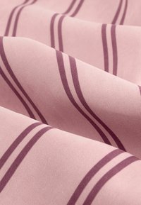Tissu en coton de couleur rose doux, avec des rayures mauves profondes. La texture est lisse, mettant en valeur un léger éclat et une belle drapé lorsqu'il se plie.