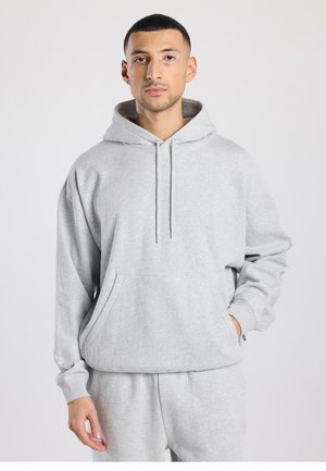 Grauer Hoodie aus weichem Stoff, mit großer Fronttasche, Kordelzugkapuze und lockerem Schnitt. Strukturierte Bündchen und Saum.
