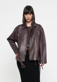 Burgundy leather moto jacket with silver hardware, asymmetrical zipper, and side pocket. Features a relaxed fit and long sleeves.