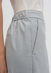 Lichtgrijze elastische taillebroek met zijzakken, op maat gemaakte design en een gladde textuur, die een schone, minimalistische silhouet benadrukt.