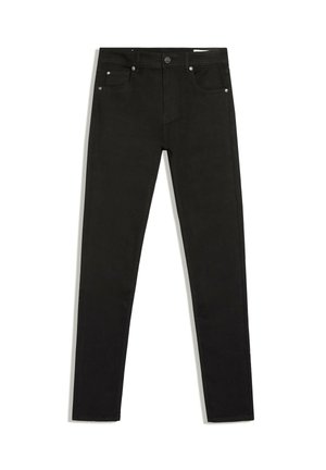 Gros plan d'une personne portant un jean noir taille haute et un pull gris court, montrant la vue de dos et de côté.